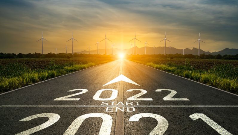 Symbolbild Startbahn mit Aufschrift 2021/2022, im Hintergrund Sonnenaufgang mit Windkrafträdern.
