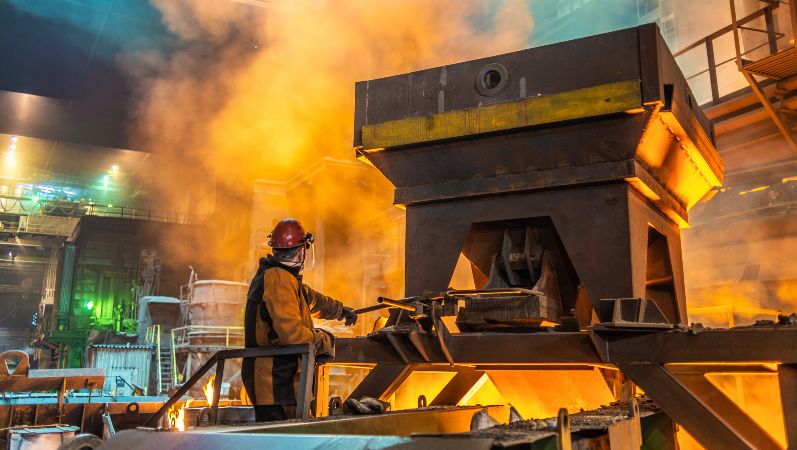 Energieintensive Industrie: Ein Arbeiter am Ofen im Stahlwerk mit glühender Hitze.