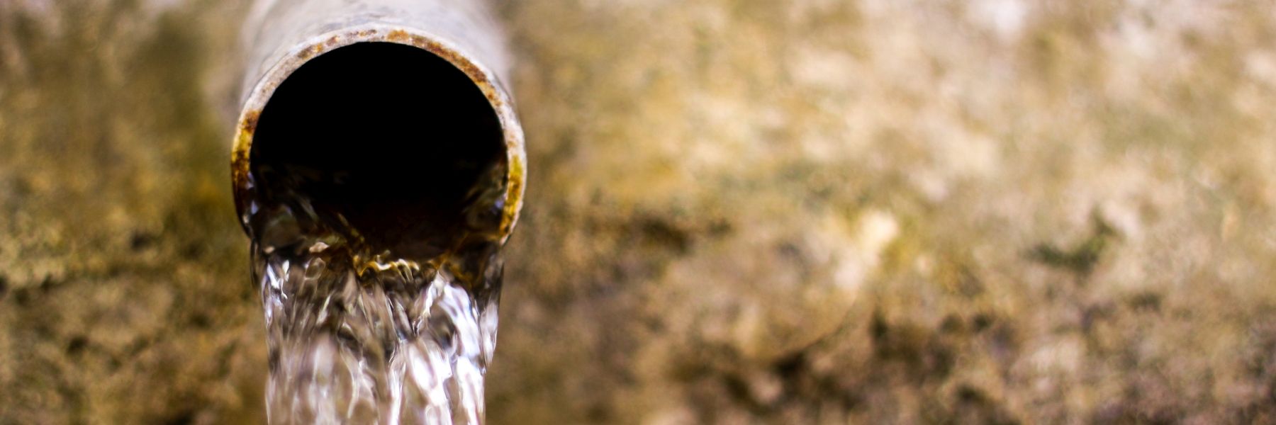 Nahaufnahme: Wasser läuft aus einem alten Metallrohr