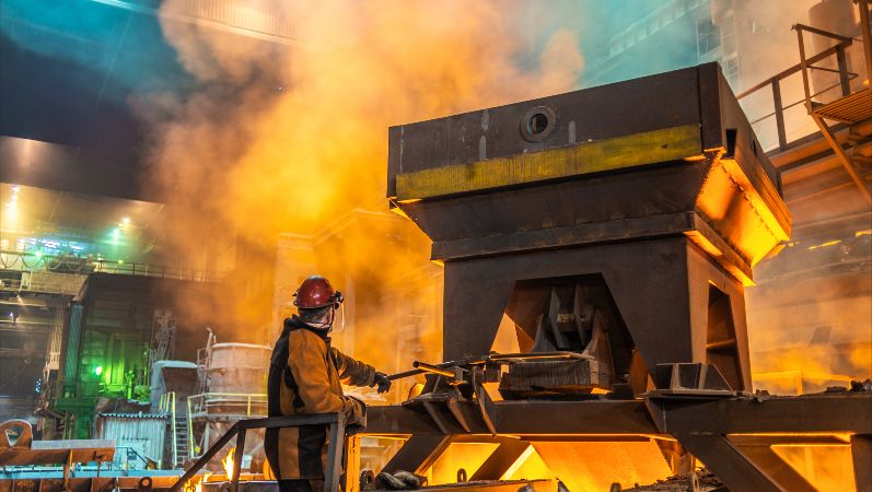 Energieintensive Industrie: Ein Arbeiter am Ofen im Stahlwerk mit glühender Hitze.
